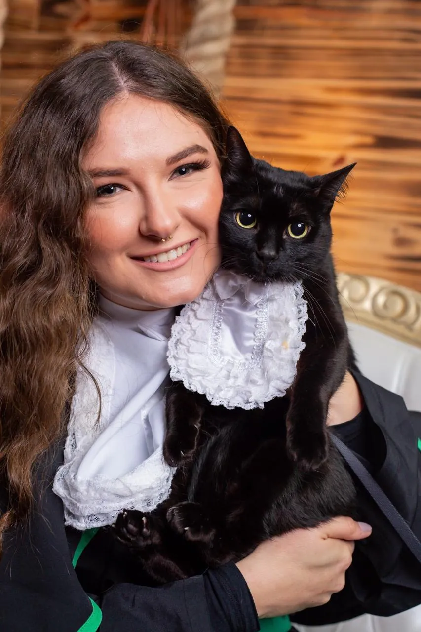 Vitória sorrindo com uma gata preta no colo